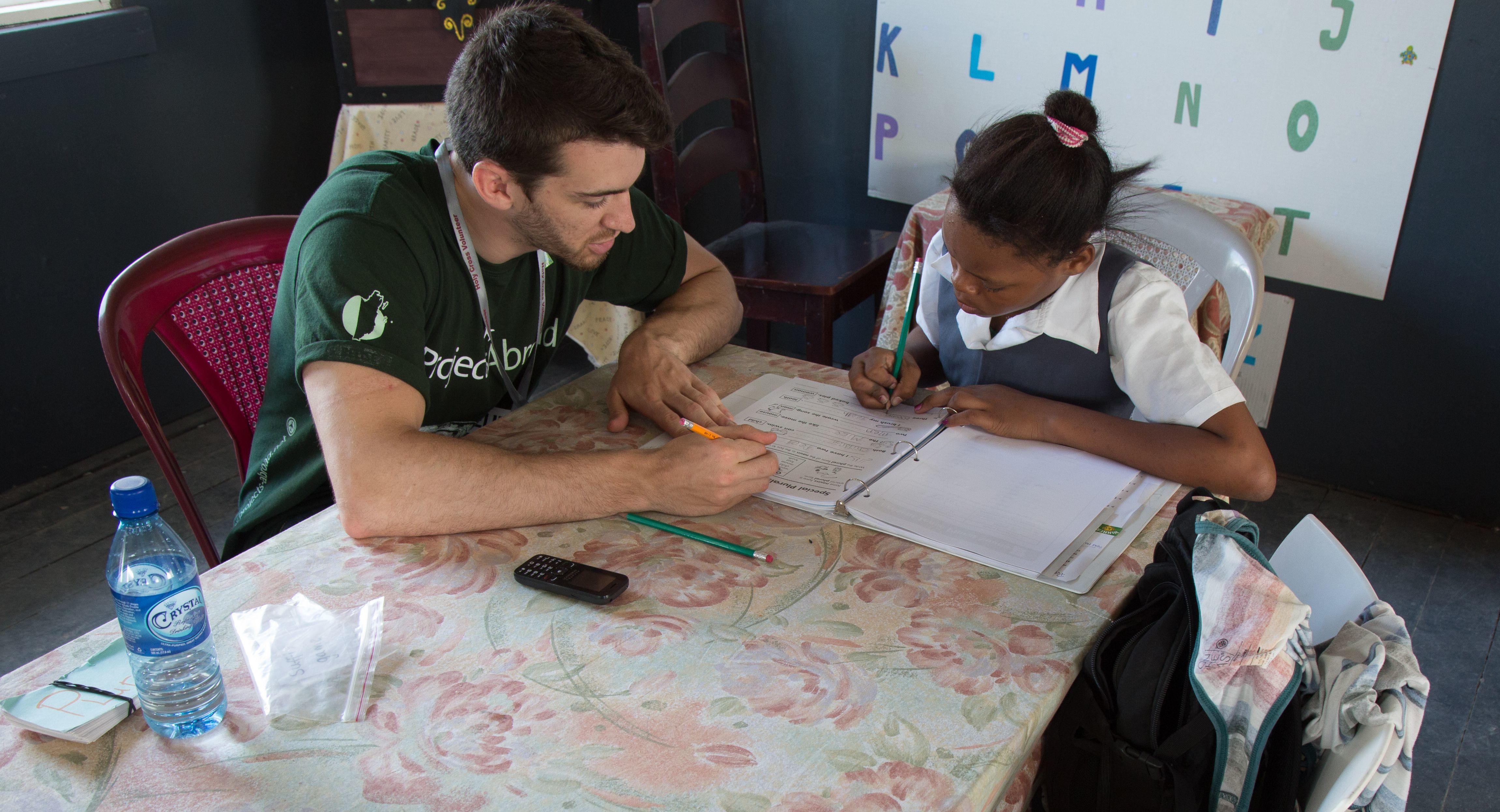 Projects Abroad volunteer conducts a one-on-one lesson with a student during his teaching work experience in Belize Teaching volunteer in Argentina helps a student with her reading skills